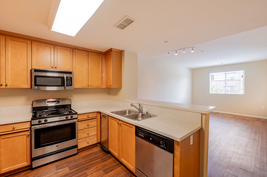 a kitchen with wooden cabinets and stainless steel appliances  at Ventana Senior Apartments, Northridge, California