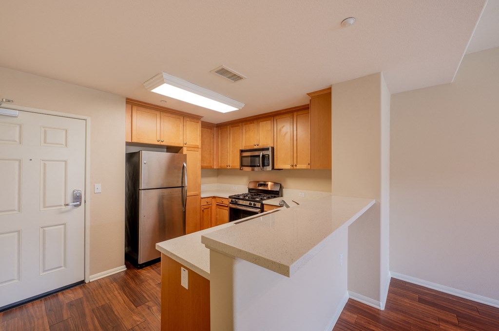 a kitchen with wood cabinets and a white counter top  at Ventana Senior Apartments, Northridge