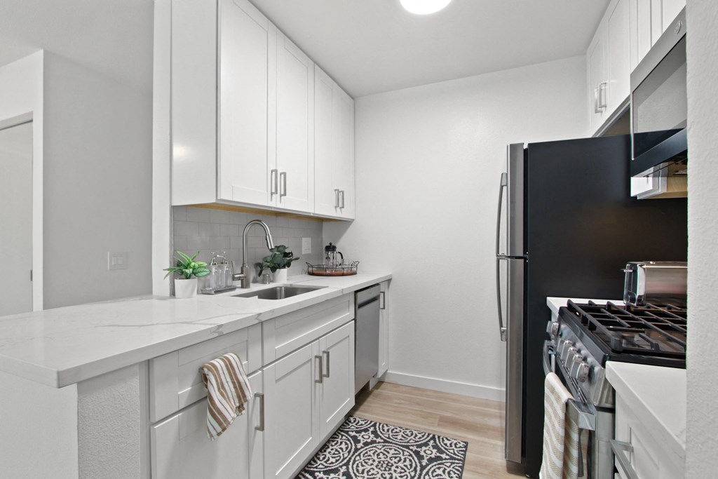 A kitchen with white cabinetry and black appliances at Harvard Manor, Irvine, CA