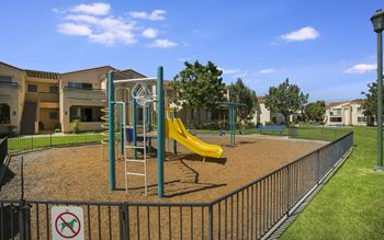 a playground with a yellow slide at the whispering winds apartments in pearland, tx