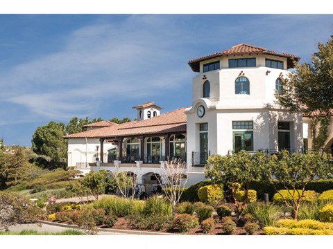 a large white building with a clock on it and a garden in front of it