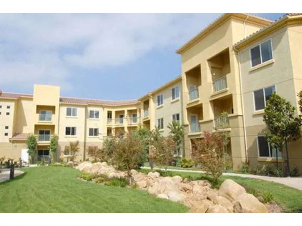 a large building with a grassy area in front of it  at Tesoro Senior Apartments, California, 91326