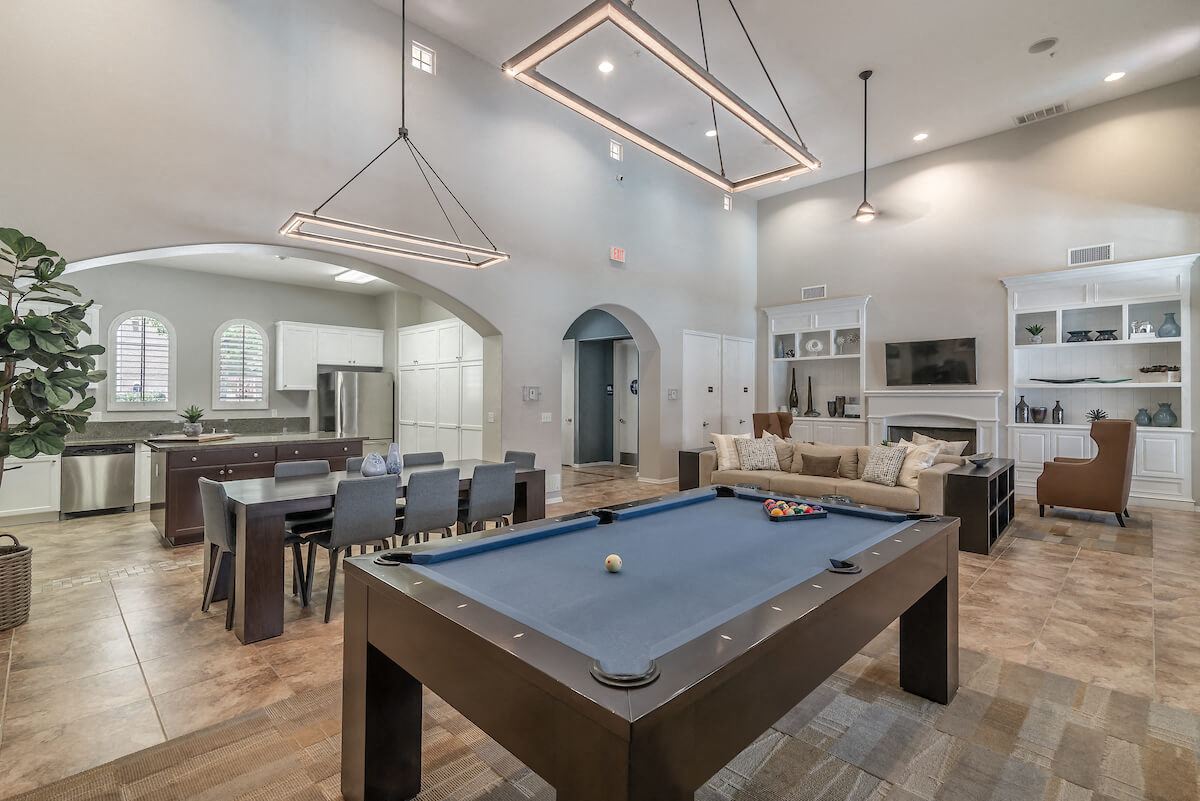 a pool table in a clubhouse with a kitchen and a living room