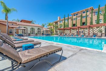 a swimming pool with lounge chairs and a building in the background  at Sonoma at Porter Ranch, Porter Ranch