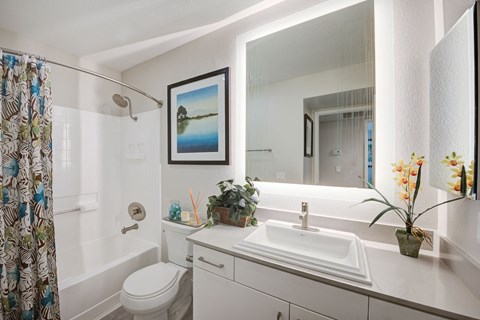 a bathroom with a white toilet next to a white bathtub and a white sink with a  at Laguna Gardens Apts., Laguna Niguel, CA