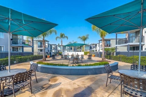 a courtyard with tables and chairs and umbrellas at Park Avenue Apartments, Long Beach, California