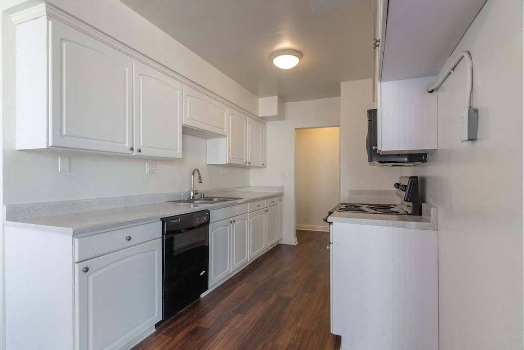 a kitchen with white cabinets and a black dishwasher at  Park Avenue Apartments, Long Beach