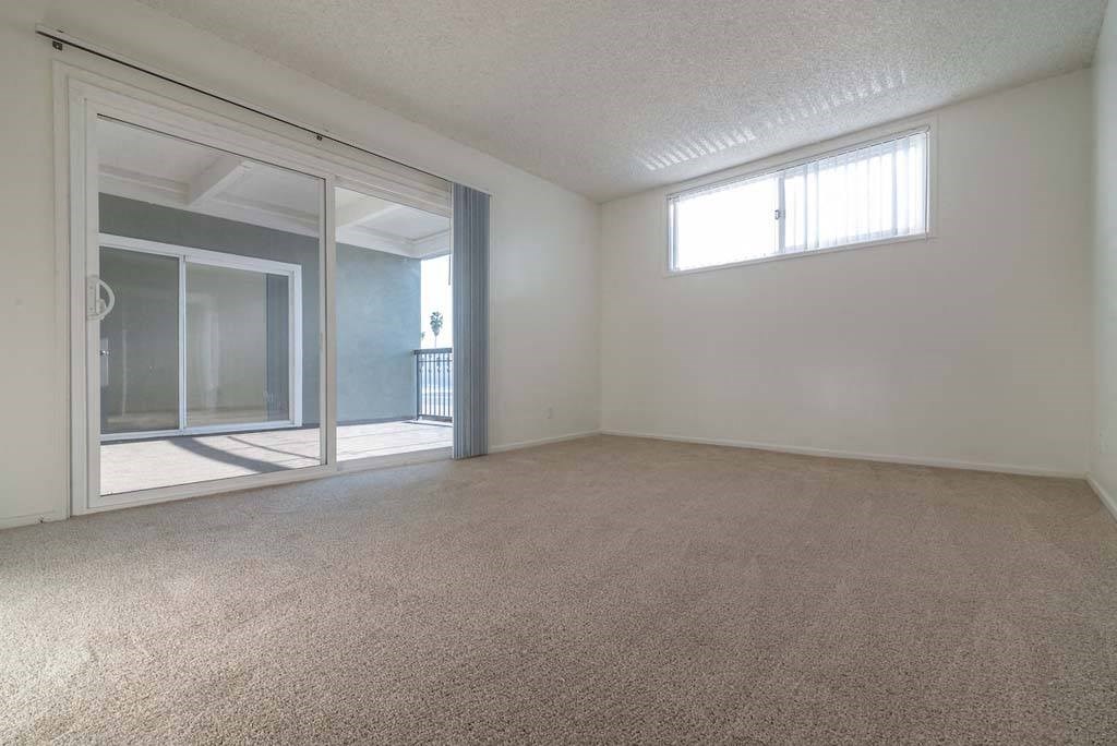 an empty room with a sliding glass door and a window at  Park Avenue Apartments, California,90815