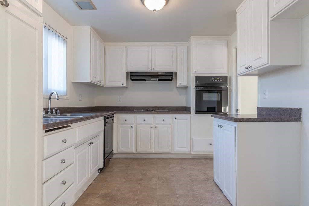 a kitchen with white cabinets and black counter tops at Park Avenue Apartments, Long Beach ,90815