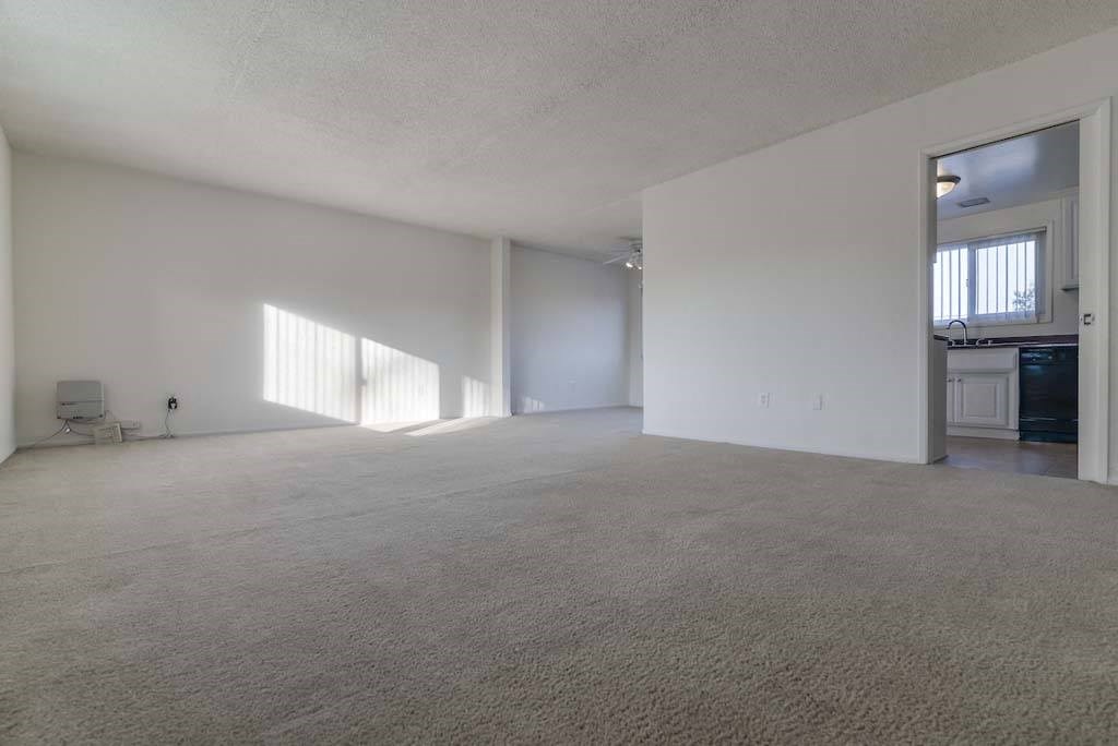 an empty living room with a kitchen in the background at  Park Avenue Apartments, California
