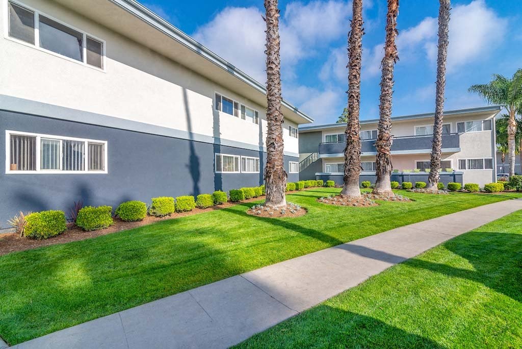 a building with a sidewalk and grass in front of it at Park Avenue Apartments, Long Beach, CA