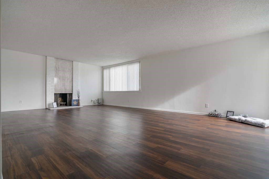 an empty living room with a fireplace and hardwood floors at Park Avenue Apartments, Long Beach, CA