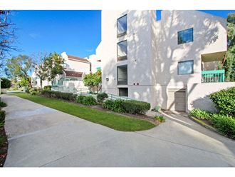 a white apartment building with a sidewalk in front of it  at Harvard Manor, Irvine, 92612 - Photo Gallery 3