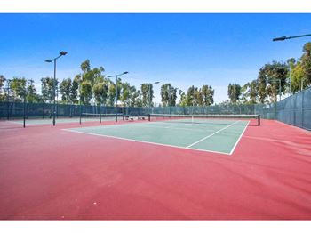 a tennis court with lights and trees in the background at Harvard Manor, Irvine, CA