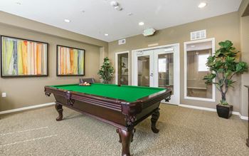 a game room with a pool table and two potted plants at Ventana Senior Apartments, California, 91326