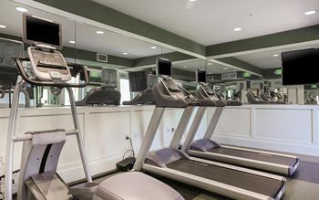 a gym with treadmills and monitors on the wall  at Ventana Senior Apartments, California, 91326