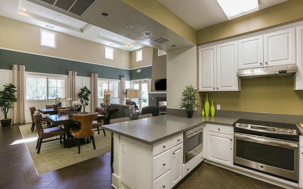 a kitchen with a stove top oven next to a table  at Ventana Senior Apartments, Northridge, CA
