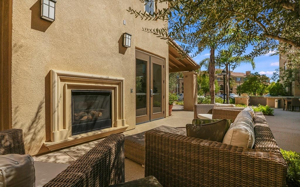 a patio with wicker furniture and a fireplace at Ventana Senior Apartments, Northridge, CA