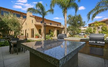 a patio with a table and chairs and a grill in front of a house at Ventana Senior Apartments, Northridge, California