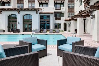 a swimming pool with blue chairs in front of a building  at Deer Creek Apartments, San Ramon, 94582 - Photo Gallery 2