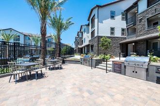a patio with tables and chairs and a grill at The Vineyards Apartments, Porter Ranch, CA