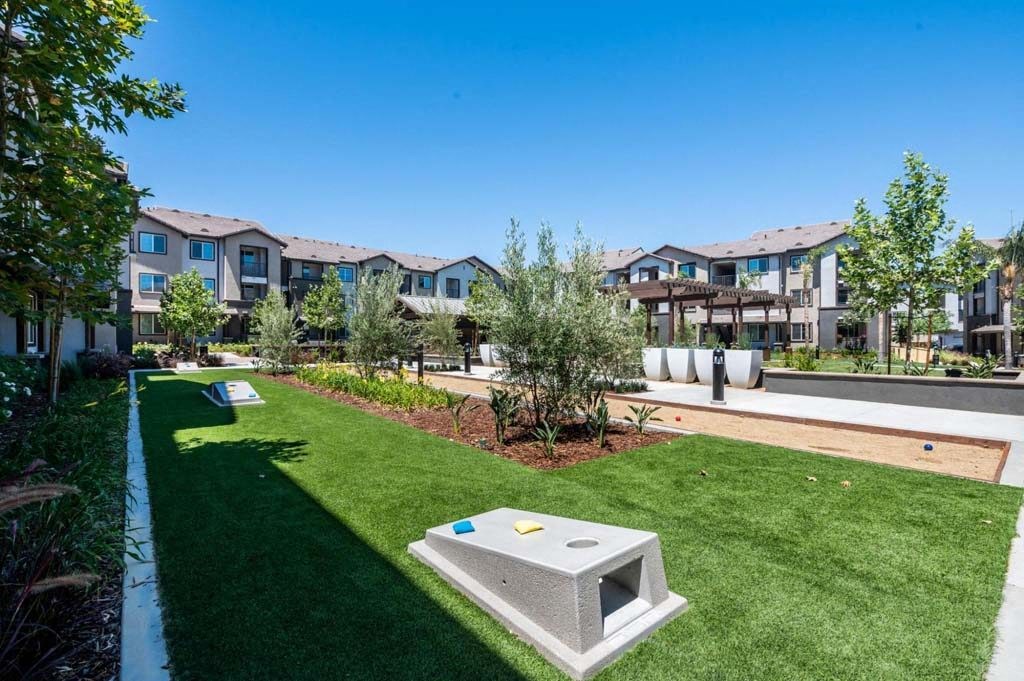 a grassy area with a fountain and apartment buildings in the background  at The Vineyards Apartments, California