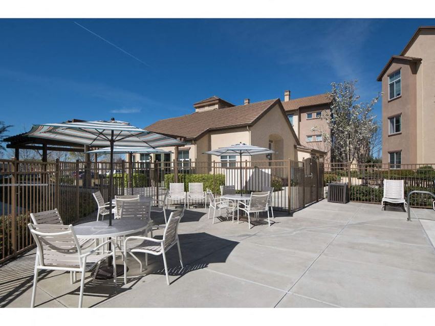 a patio with tables and umbrellas and a building in the background a patio with tables and umbrellas and a building in the background at Seville at Gale Ranch, California