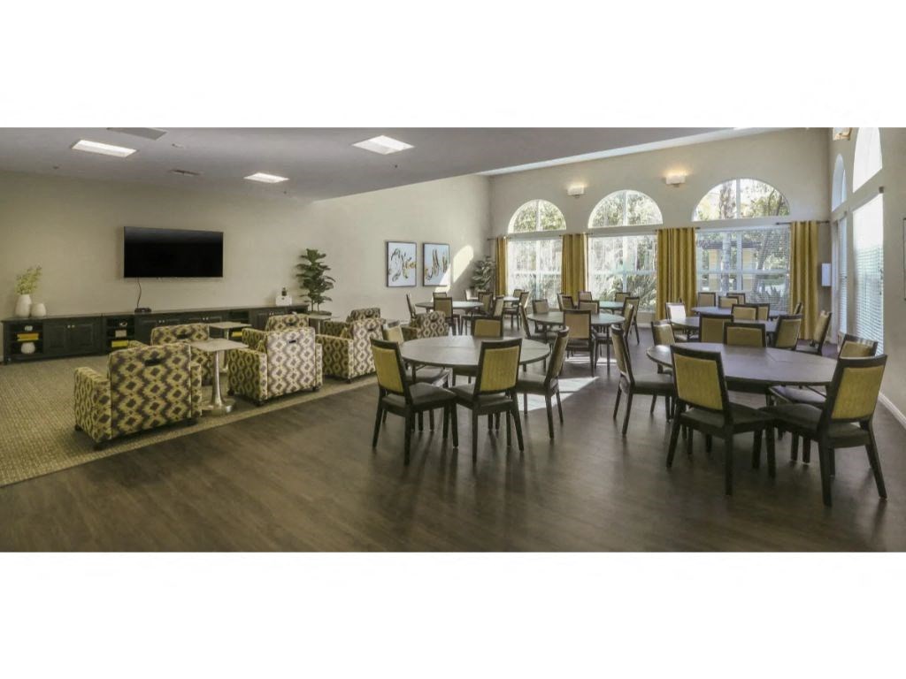 a large room with tables and chairs and a flat screen tv  at Tesoro Senior Apartments, Porter Ranch, CA