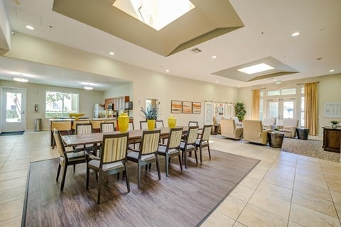 a resident clubhouse with a long table with chairs and a kitchenette in the background  at Tesoro Senior Apartments, Porter Ranch, CA, 91326