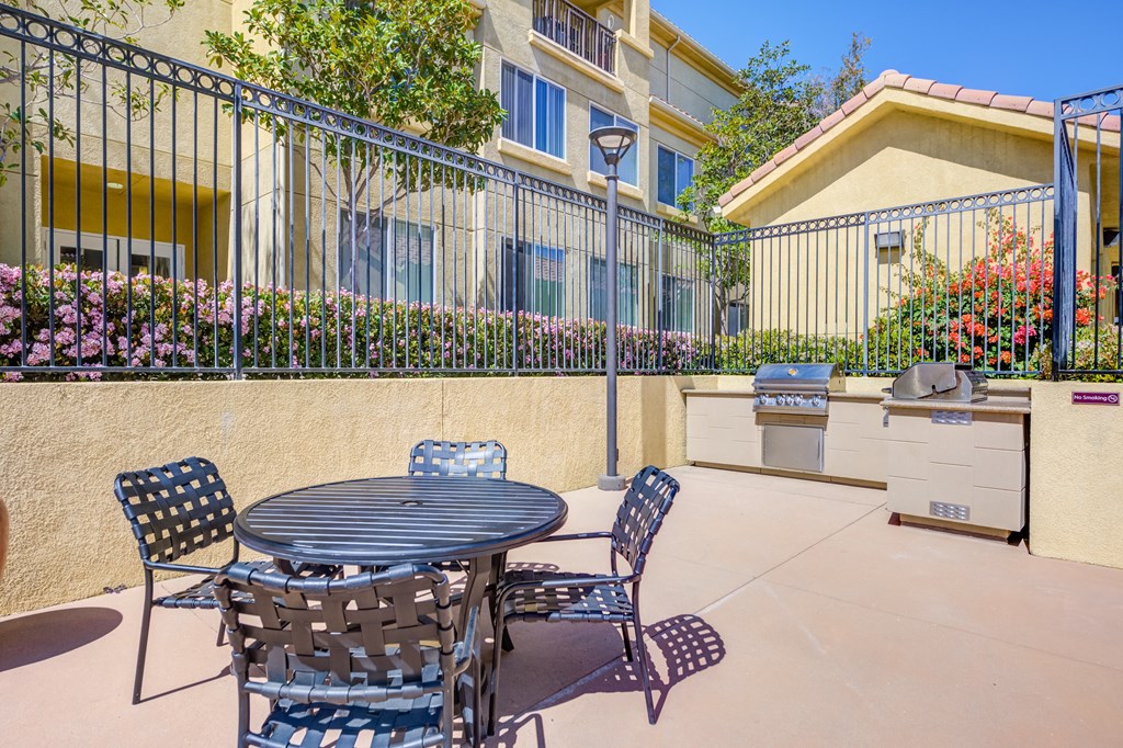 a patio with a table and chairs and a grill at Tesoro Senior Apartments, Porter Ranch