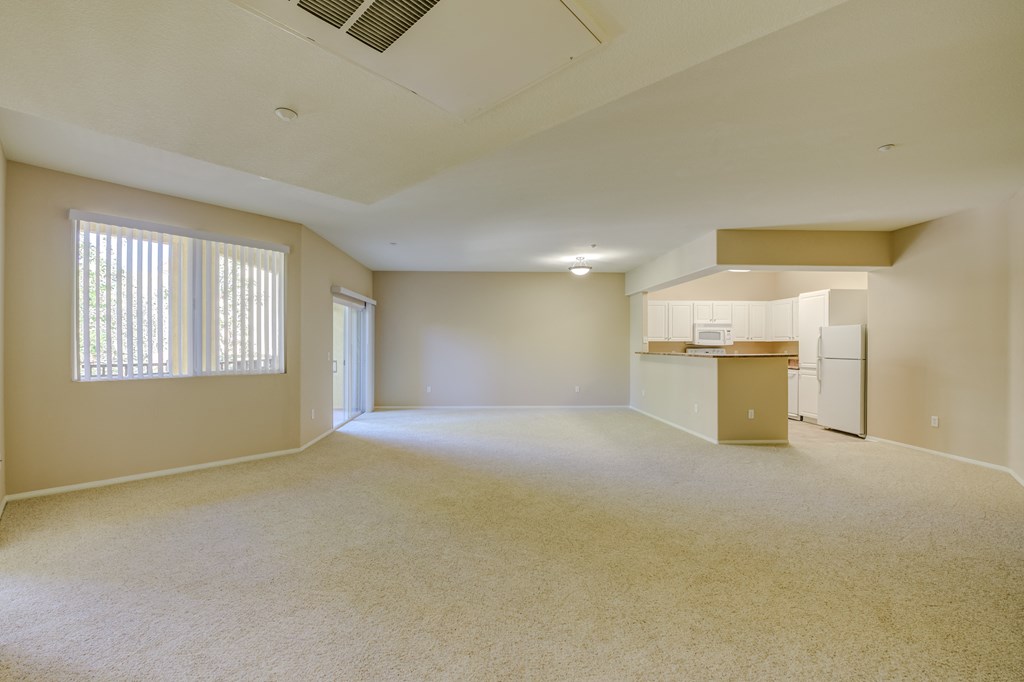 an empty living room with a kitchen in the background  at Tesoro Senior Apartments, Porter Ranch, CA