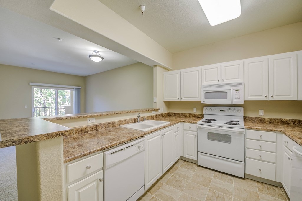 a kitchen with white cabinets and white appliances  at Tesoro Senior Apartments, Porter Ranch, CA, 91326