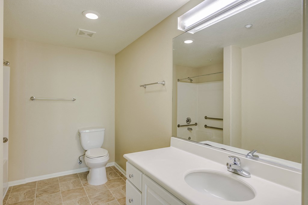 a bathroom with a sink toilet and mirror  at Tesoro Senior Apartments, California