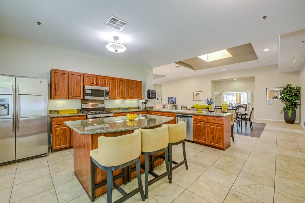 a large kitchen with granite countertops and stainless steel appliances  at Tesoro Senior Apartments, California, 91326
