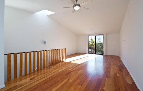 an empty living room with a wood floor and a ceiling fan