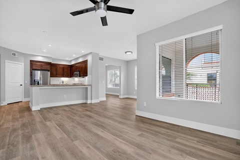 A spacious living room with a ceiling fan and hardwood flooring.