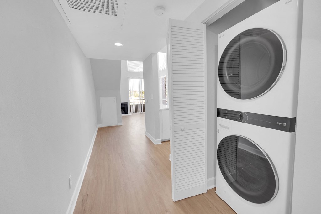 a washer and dryer in a white room with white walls and wood floors