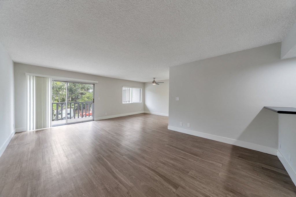 the living room and dining room of an apartment with wood flooring and a balcony at The Mark Culver City, Culver City
