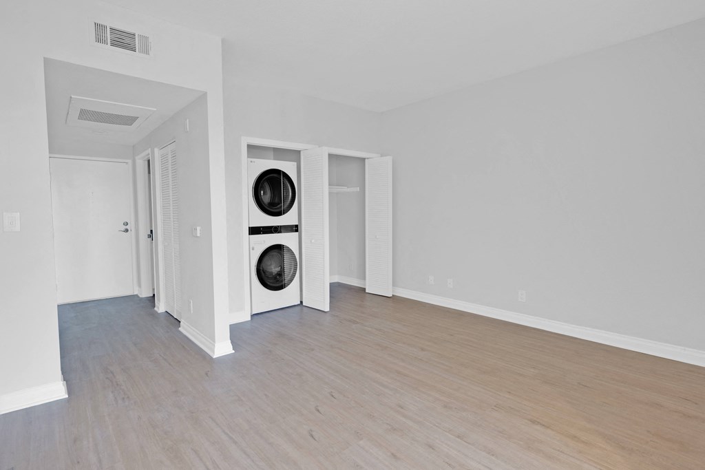 a living room with a wood floor and white walls and a washer and dry