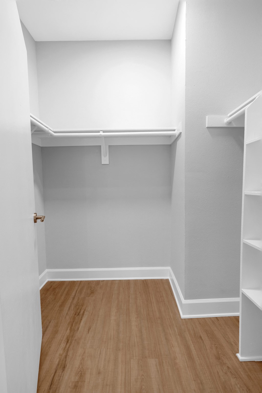an empty room with white shelves and a wood floor