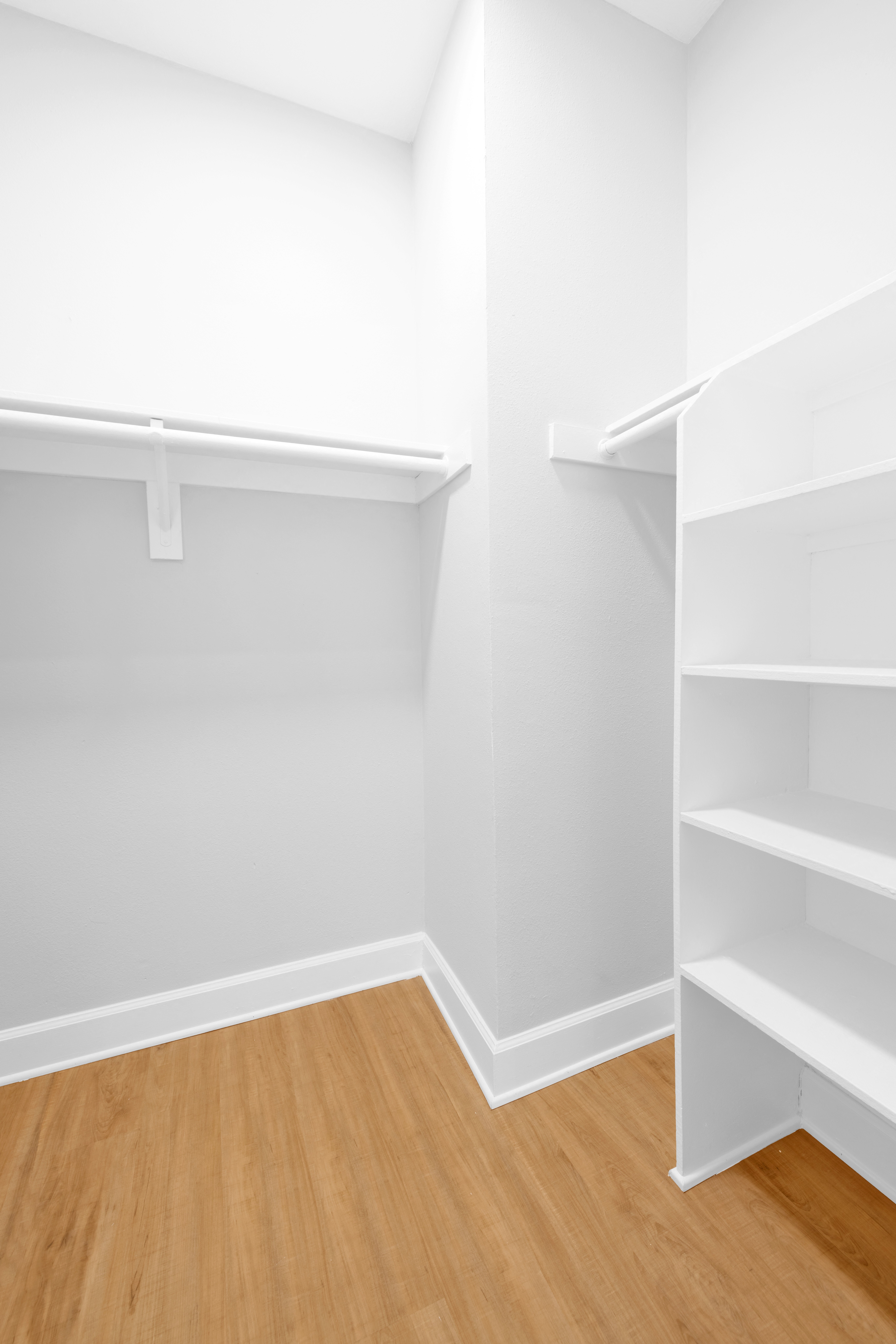 an empty room with white shelves and a wood floor
