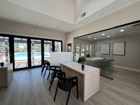 A reception area with a white desk and black chairs.