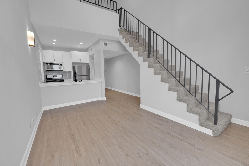 a renovated living room with a staircase and a kitchen