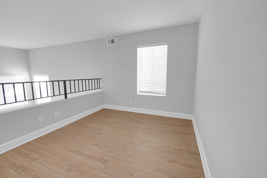 an empty living room with a wooden floor and a balcony