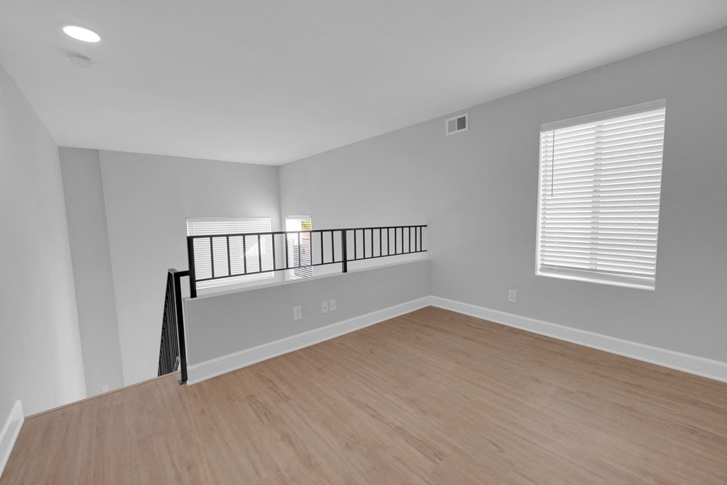 an empty living room with a wooden floor and a balcony