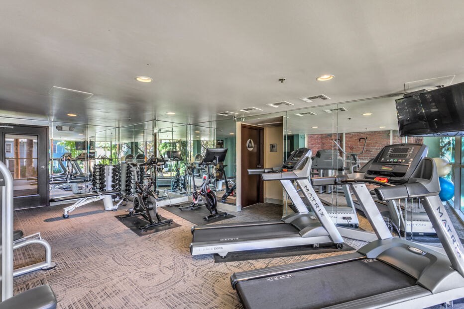 a gym with treadmills and other exercise equipment in a building with glass walls