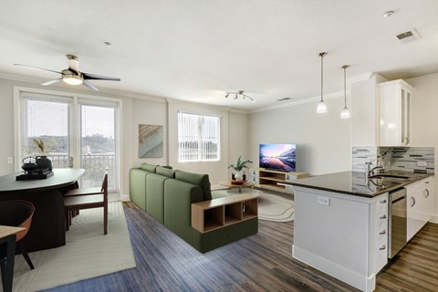 A modern kitchen with a green sofa and a dining table. at Apex Mission Valley, San Diego, CA, 92108