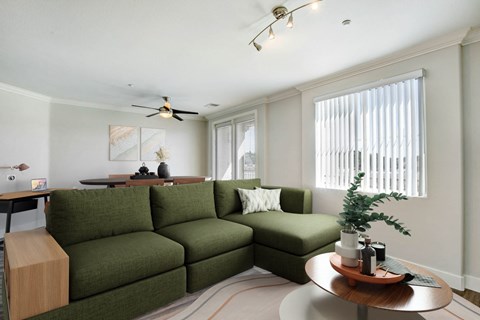 A living room with a green couch and a wooden side table. at Apex Mission Valley, California, 92108
