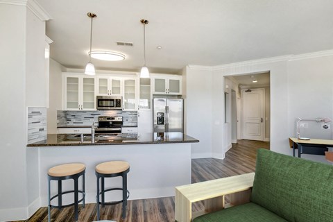 A kitchen with a bar area and a green couch. at Apex Mission Valley, San Diego