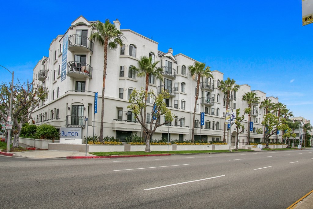 a white building with palm trees in front of an empty street at Burton, Los Angeles, California